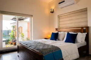 Stylish and comfortable bedroom at Kappad Beach House by Kisah Stays, featuring a cozy bed, elegant decor, and warm lighting. Designed for relaxation, this serene space offers a peaceful retreat with a luxurious ambiance, perfect for a restful stay by the beach in Kozhikode, Kerala