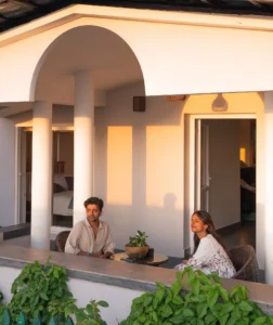 A couple enjoying a peaceful moment on the veranda at Kappad Beach House by Kisah Stays, overlooking the serene courtyard. Surrounded by lush greenery and a refreshing coastal breeze, this tranquil setting offers the perfect spot to unwind and soak in the beauty of Kozhikode, Kerala.