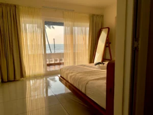 Breathtaking view of the beach from the bedroom at Kappad Beach House by Kisah Stays. Through the window, the golden sands and shimmering Arabian Sea create a picturesque backdrop, complementing the cozy and serene ambiance of this luxurious beachfront retreat in Kozhikode, Kerala
