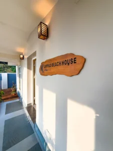 Kappad Beach House by Kisah Stays – a beautifully designed name board displayed in the veranda overlooking the serene courtyard. Surrounded by lush greenery and a peaceful coastal ambiance, the board welcomes guests to this luxurious beachfront retreat in Kozhikode, Kerala.