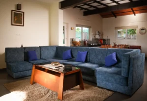 Cozy and elegant living room at Kappad Beach House by Kisah Stays, featuring stylish furniture, warm lighting, and a spacious layout. The room is designed for comfort, complete with a large TV and inviting seating, creating the perfect space to relax and unwind by the beach in Kozhikode, Kerala.