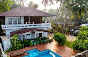 Stunning aerial drone shot of Kappad Beach House by Kisah Stays, showcasing its beautiful exterior, private pool, and lush surroundings. Nestled along the serene coastline of Kozhikode, Kerala, this beachfront retreat offers breathtaking views of the Arabian Sea and a perfect blend of luxury and nature